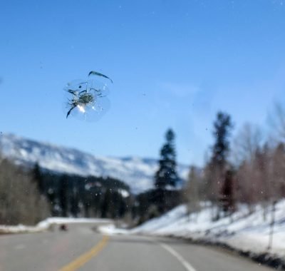 Chipped windshield with road and snow covered mountains rock chip on a windshield